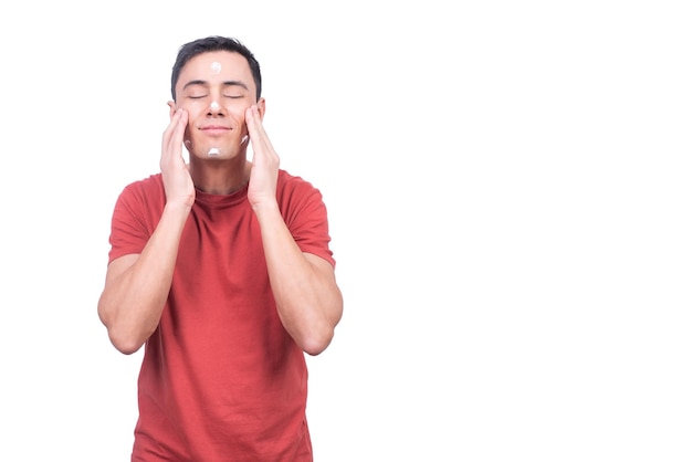 Content man applying moisturizing facial cream against whitebackground