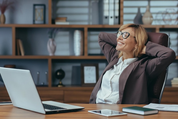 A content senior businesswoman takes a welldeserved break lounging in her chair with a satisfied