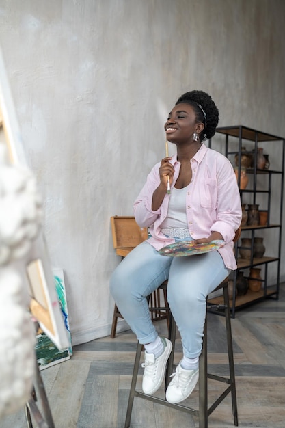 Contented african artist in pink clothes looking inspired