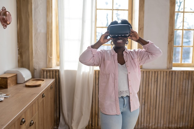 Contented african woman in pink clothes in VR galsses