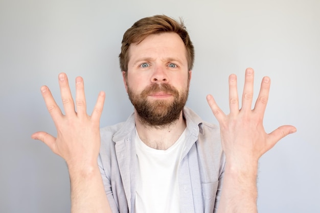 Contented calm man in a shirt shows the number ten on fingers or his newly washed hands