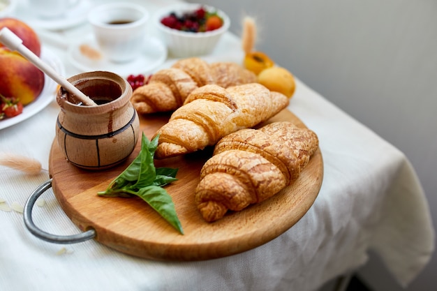 Continental breakfast table served with traditional French croissant, fruits and coffee, copy space, frame.