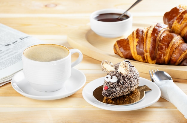 Continental breakfast with fresh chocolate croissants, a cake made in the form of a mouse and coffee . Delicious pastries with coffee espresso.