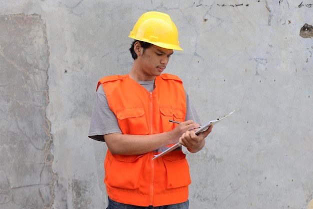 Contractor man in helmet checking document on clipboard during construction project