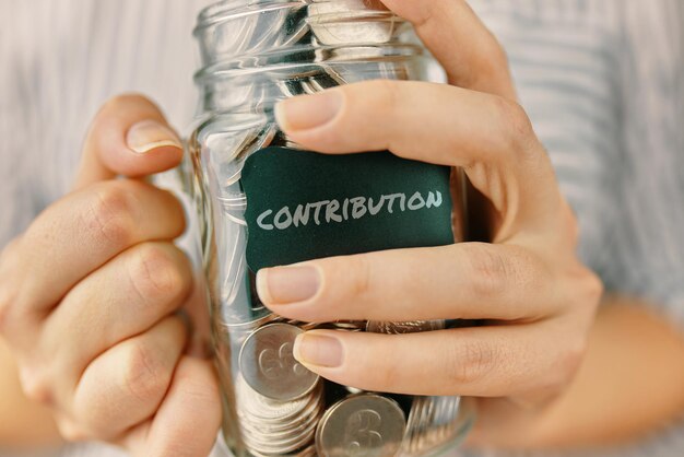 Photo contributions in glass jar woman holds a bottle of coins financial literacy