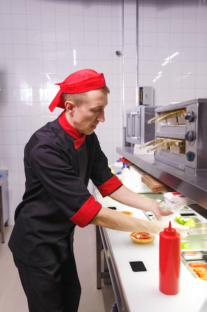 Cook adding a ketchup on burger