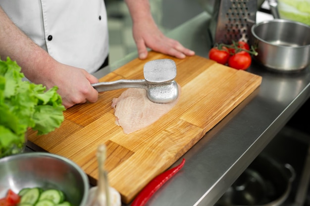 Cook beating a chicken breast with a hammer, close-up. Diet, healthy low-calorie food, weight loss concept