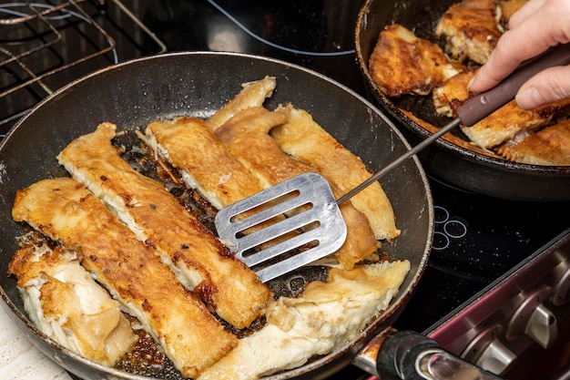 The cook checks the readiness of the fish with a fork