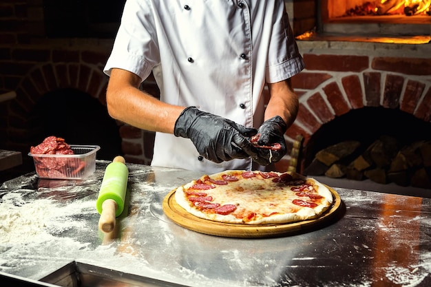 Cook Chef making delicious pizza at the restaurant closeup