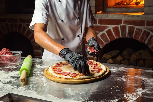 Cook Chef making delicious pizza at the restaurant closeup