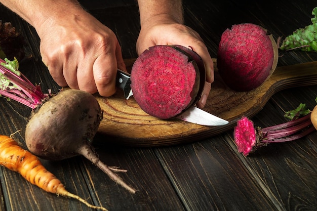 The cook cuts beetroot with a knife to prepare delicious borscht Ukrainian national cuisine