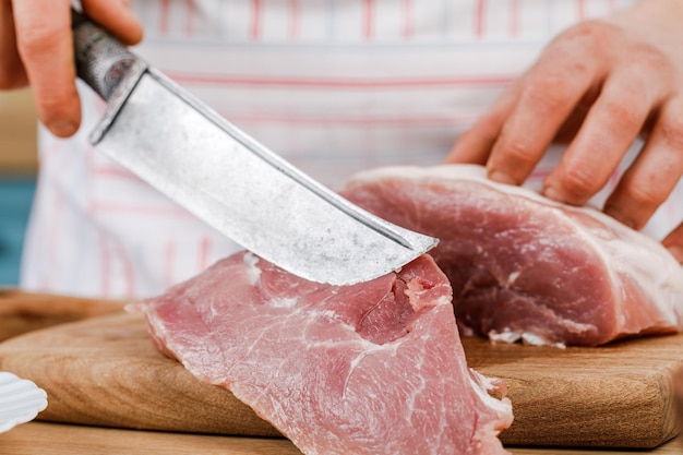 Cook cuts a piece of fresh meat cuts meat in the kitchen