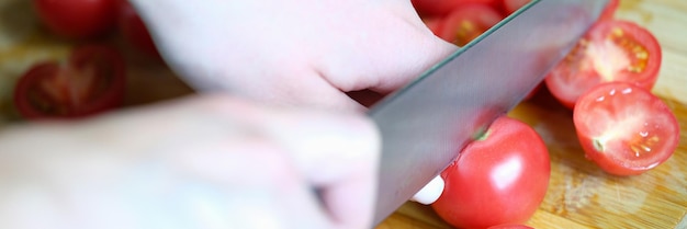 Cook cuts tomatoes on wooden board closeup benefits of vitamins and cooking tomato concept