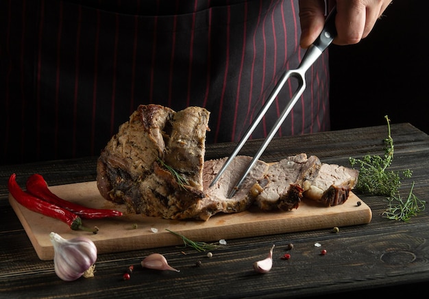 Cook hand with a fork and juicy grilled beef steak Selected marbled meat sliced on a wooden board