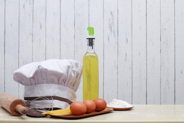 Cook hat with cooking ingredients on kitchen wooden table