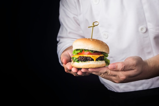 A cook holds a delicious beef hamburger just made