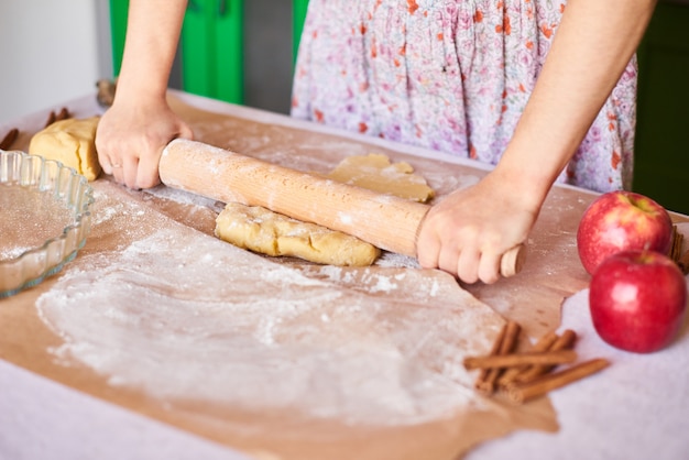 Cook at home. Woman kneading dough for the apple pie on kitchen table. Rustic style