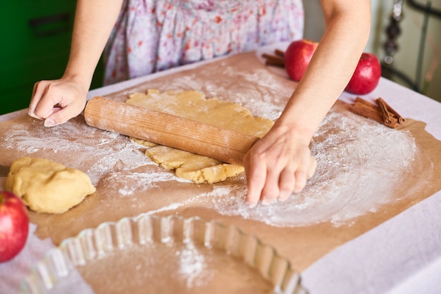 Cook at home. Woman kneading dough for the apple pie on kitchen table. Rustic style