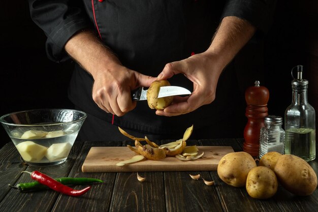 The cook peels potatoes for cooking French fries Working environment in the kitchen of a restaurant