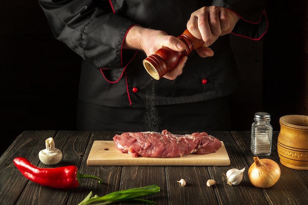 The cook prepares beef meat adds pepper