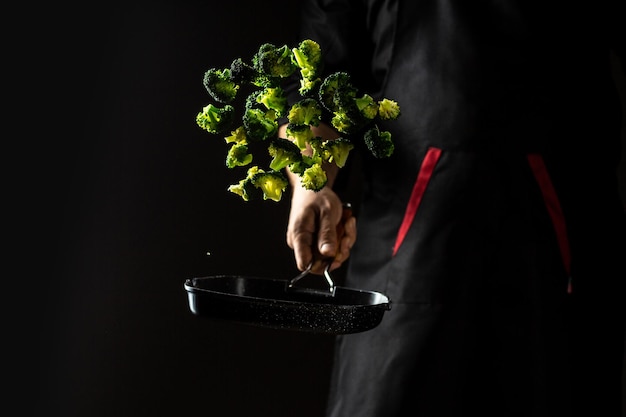 Cook prepares vegetables in a freeze motion of a cloud midair on black Restaurant menu dieting cookbook recipe