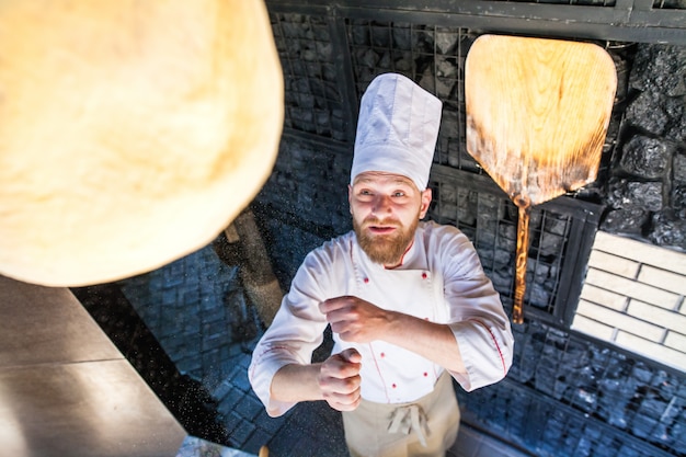 Cook preparing pizza in a restaurant.