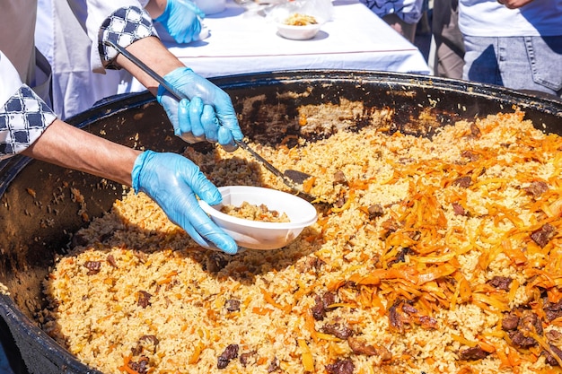 The cook puts hot pilaf in a plastic disposable plate. Asian Street food