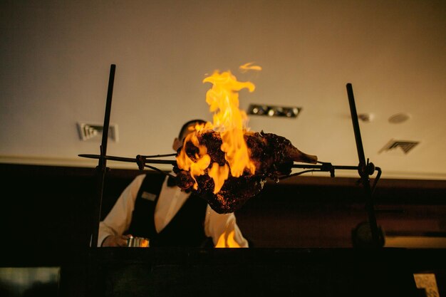 A cook in a restaurant prepares an appetizing roast lamb with a crispy crust on a spit.Meat on fire.