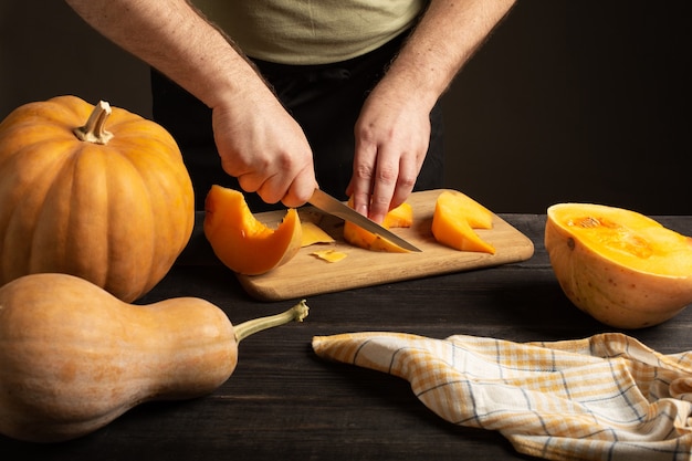 The cook slices the pumpkin for baking. 