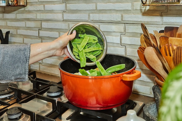 Cook throws snow peas into pan on gas stove