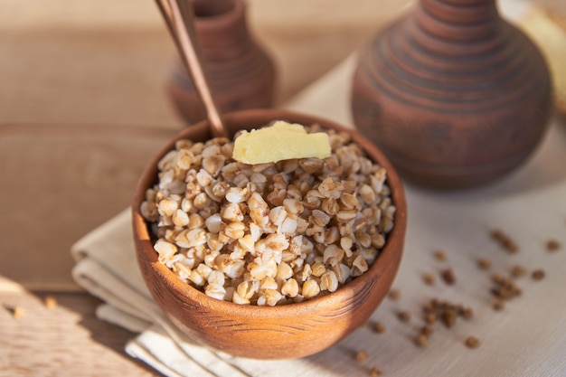 Cooked buckwheat cereal in brown clay bowl on wooden table. gluten free grain for healthy diet