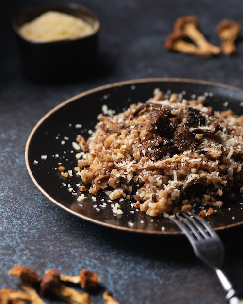 Cooked buckwheat with dried mushrooms on a plate sprinkled with Parmesan.