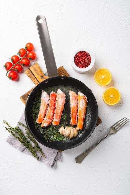 Cooked crab legs set, in cast iron frying pan, on white stone table background, top view flat lay