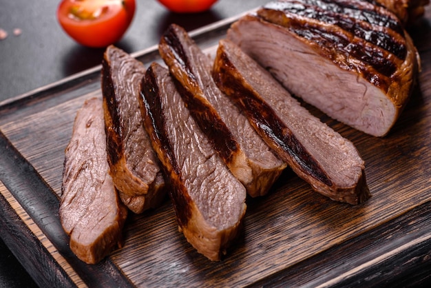 Cooked grilled Chuck eye roll steak on a chopping Board. Dark background