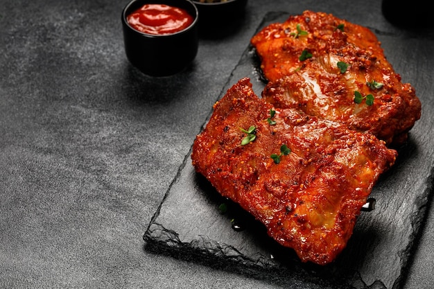 Cooked Marinated pork bbq ribs Baked Ribs in marinade sauce on board and dark background Copy space