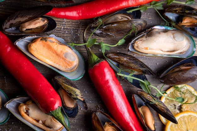 Cooked mussels on a wooden background the background is decorated with greens pepper microgreens salt