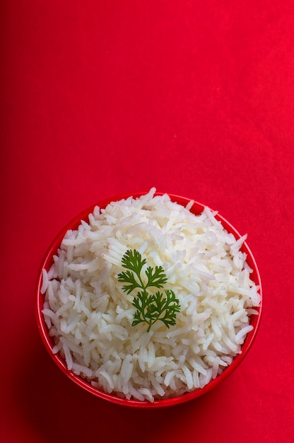 Cooked plain white basmati rice in a red bowl on red surface