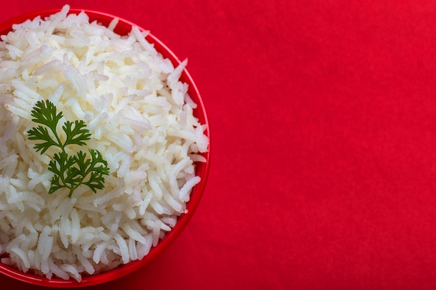 Cooked plain white basmati rice in a red bowl on red