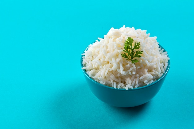 Cooked plain white basmati rice with corriander in a blue bowl on blue