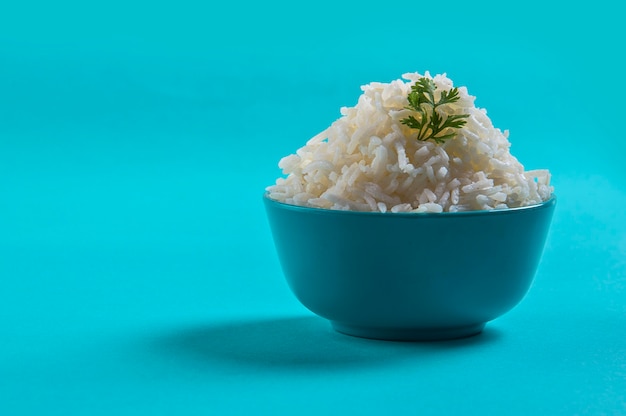 Cooked plain white basmati rice with corriander in a blue bowl on blue