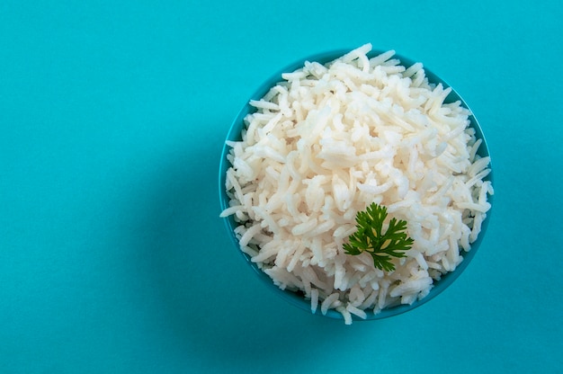 Cooked plain white basmati rice with corriander in a blue bowl on blue