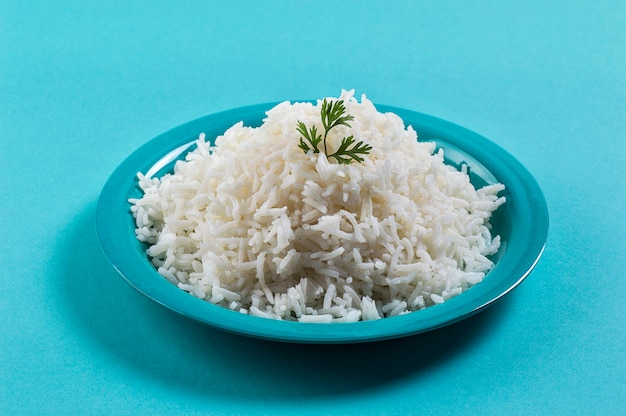 Cooked plain white basmati rice with corriander in a blue plate on blue surface