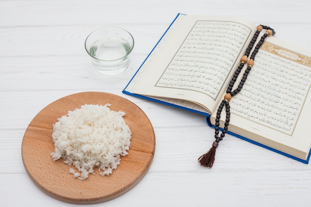 Cooked rice with Quran and beads on table