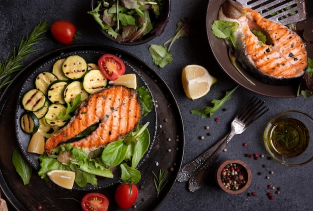 Cooked salmon fish with vegetables on dark background