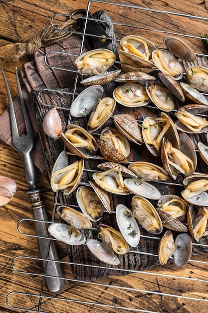 Cooked shells Clams vongole on a grill with garlic and rosemary Wooden background Top view