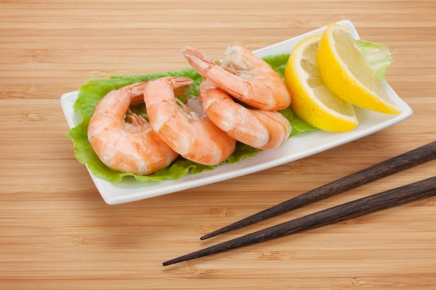 Cooked shrimps with lemon and chopsticks