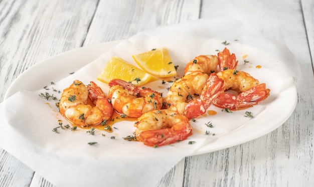 Cooked shrimps with thyme and lemon wedges on serving plate