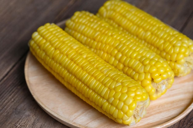 Cooked sweet corn on wooden plate background ripe corn cobs steamed or boiled sweetcorn for food vegan dinner or snack