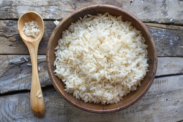 Cooked white rice in a bowl next to a wooden spoon on a wooden table Generative AI