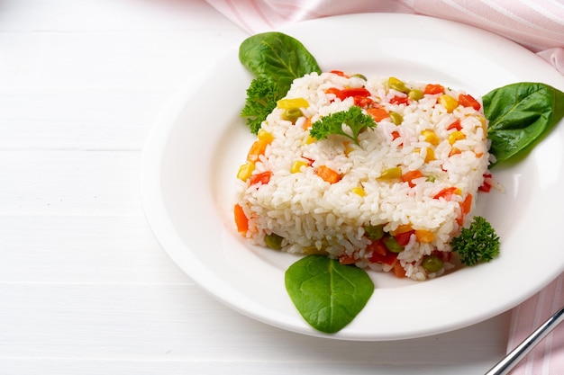 Cooked white rice mixed with colorful vegetables on white plate